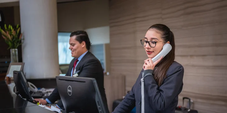 A front office manager over the phone with a client.