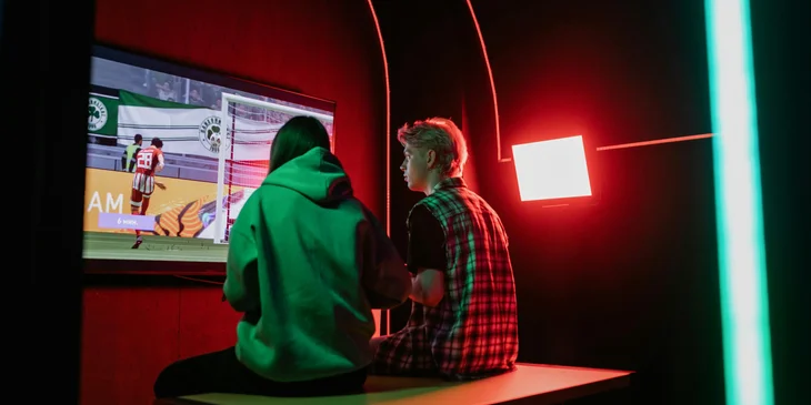 Two game programmers testing a product prototype on a wall-mounted television.