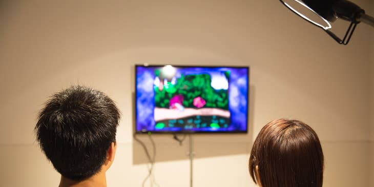 two Game Programmers testing a product prototype on the wall-mounted television