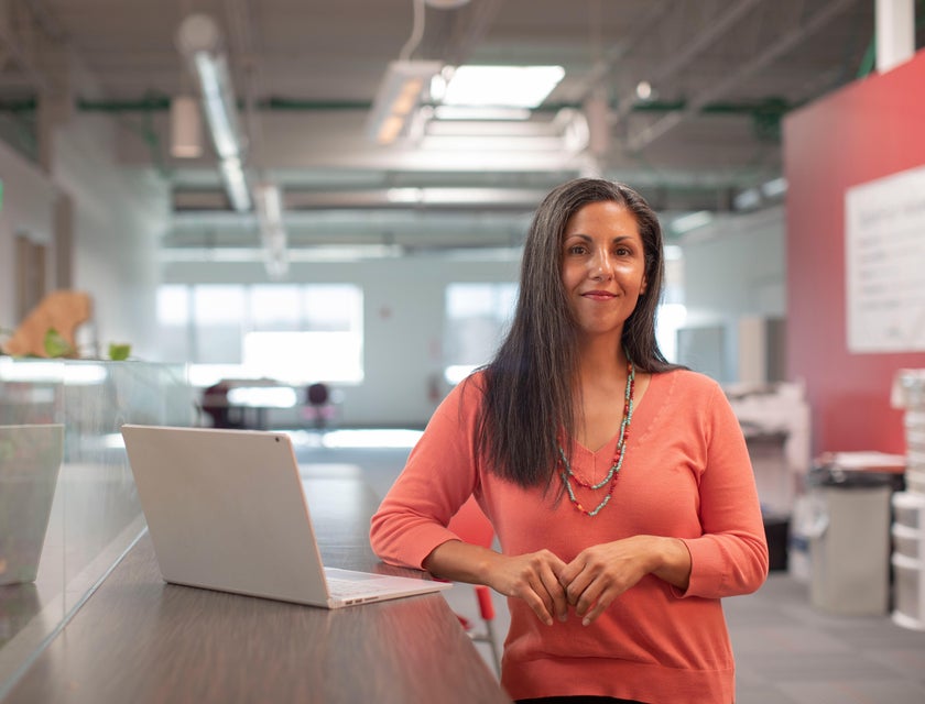 Female General Manager standing inside the office with an open laptop beside her