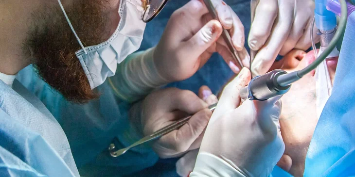 A general surgeon performs a surgical procedure on a young lady.