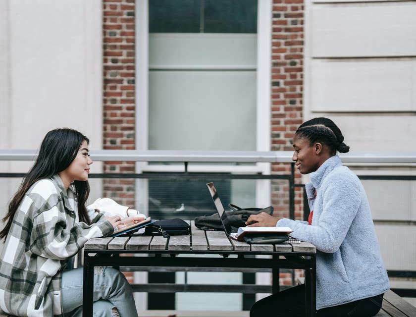 Graduate Trainee keeps a log on things learned in a laptop while a colleague was taking notes