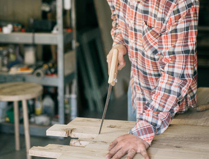 Handyman using a handsaw on wooden boards