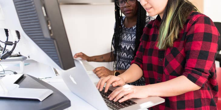 Female Head of Operations showing something on her laptop to her colleague
