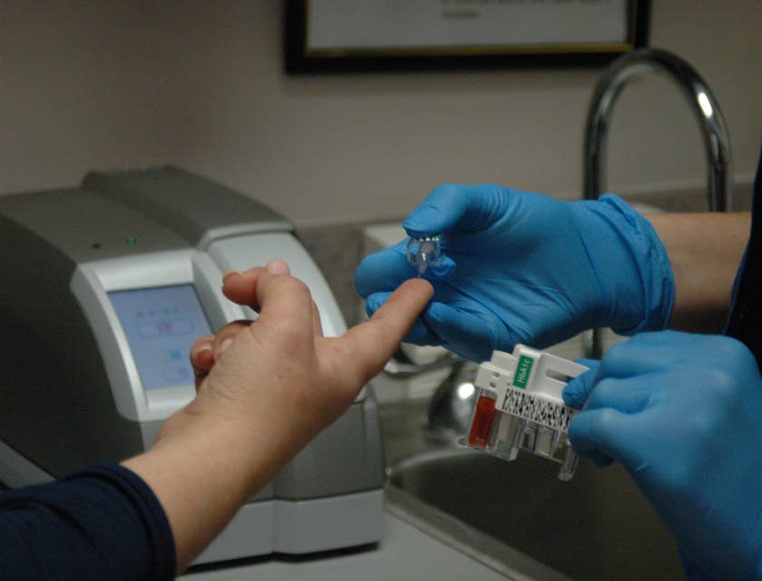 Healthcare Assistant taking blood glucose levels of the patient.