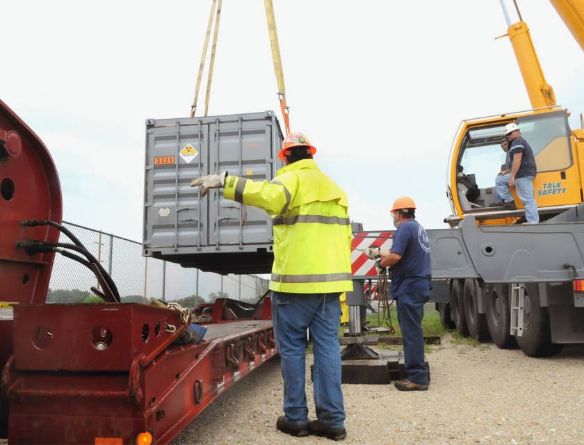 The Heavy Equipment Operator maneuvers the machine to transfer a container.
