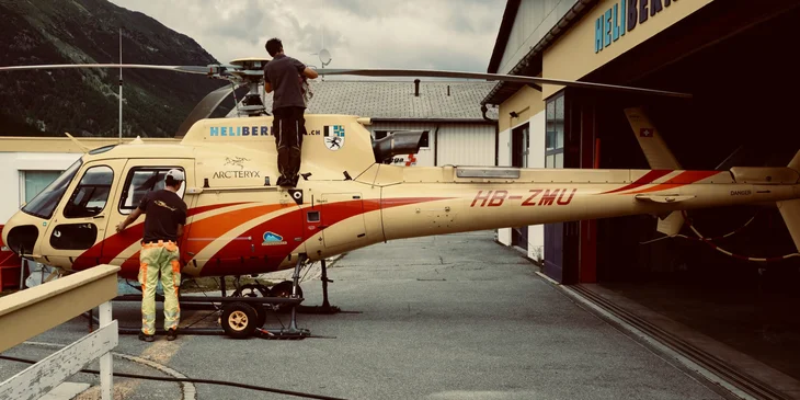 Two helicopter mechanics conducting an inspection on a helicopter.