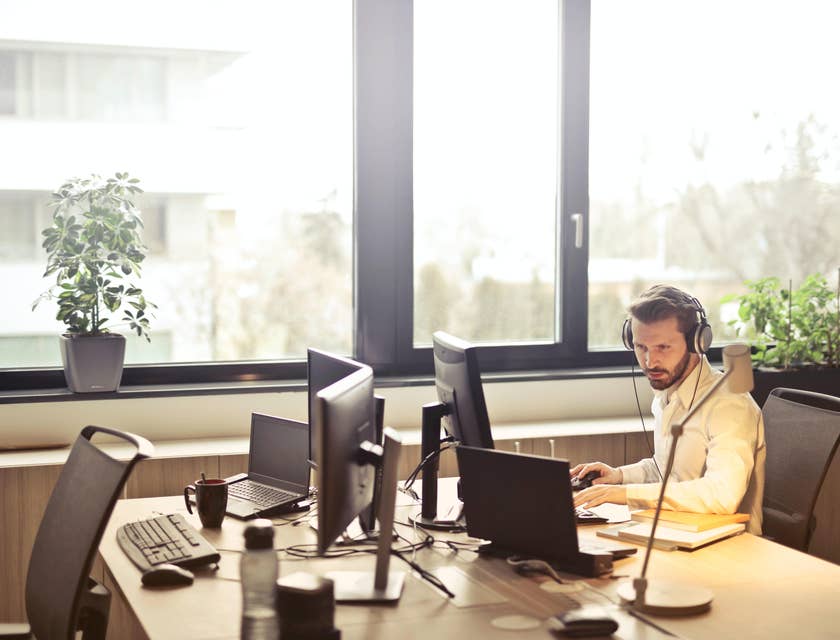 Help Desk Analyst wearing a headset at his workstation and troubleshooting with the client over the phone