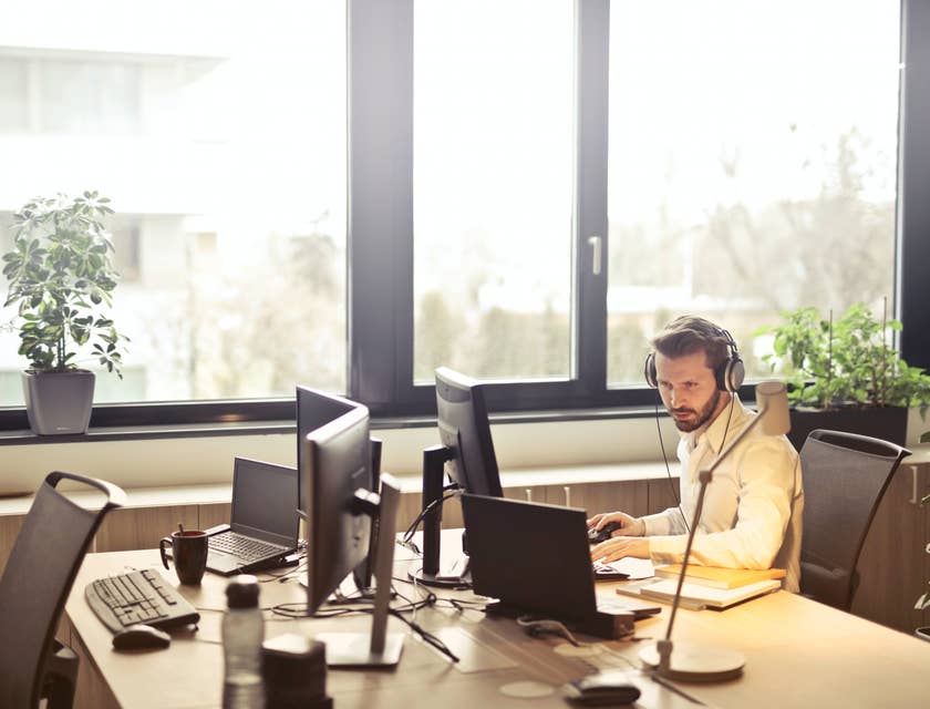 Help Desk Analyst wearing a headset at his workstation and troubleshooting with the client over the phone