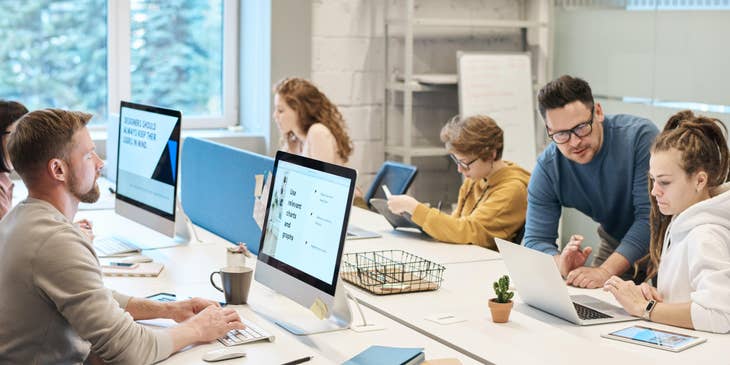 Help Desk Manager providing guidance on a member's query while the rest of the team works individually