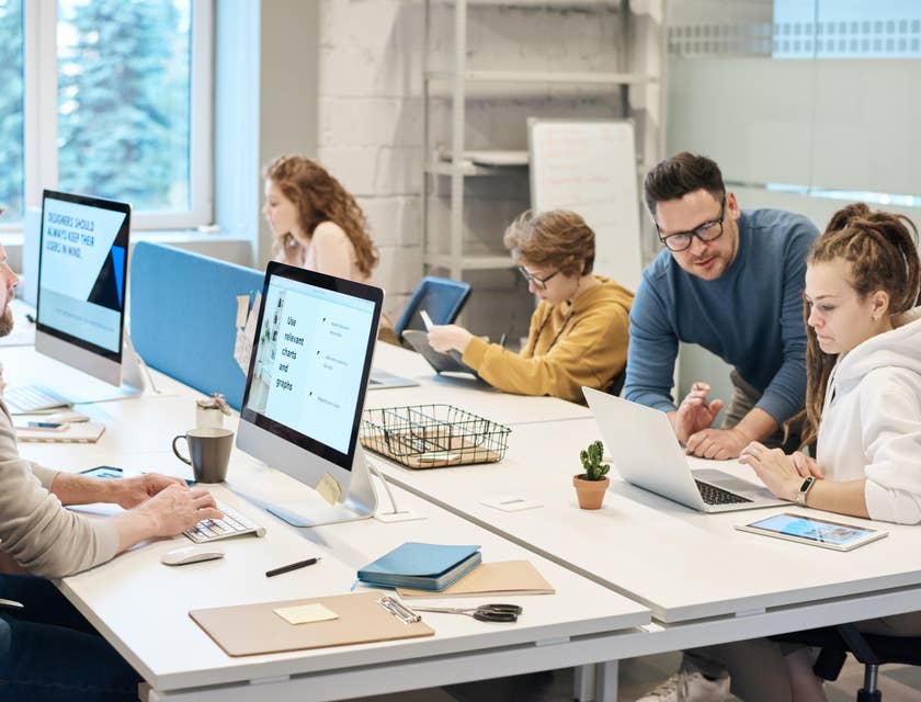 Help Desk Manager providing guidance on a member's query while the rest of the team works individually