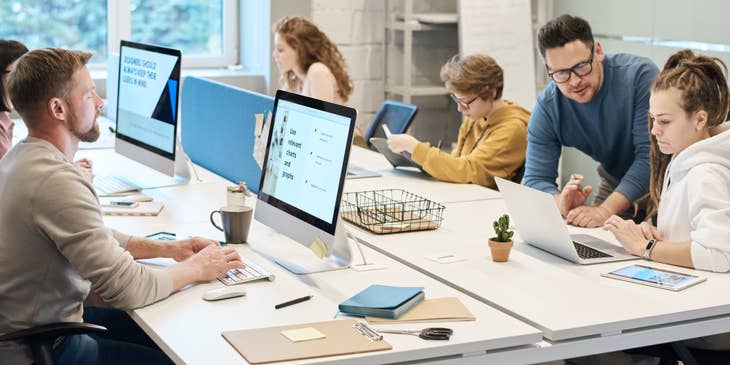 Help Desk Manager providing guidance on a member's query while the rest of the team works individually