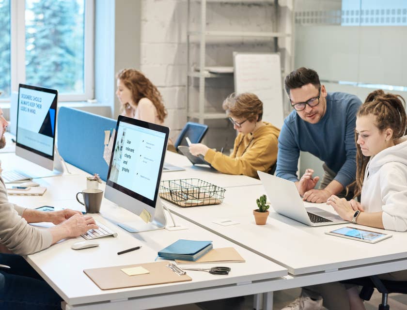 Help Desk Manager providing guidance on a member's query while the rest of the team works individually
