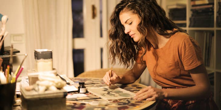 An illustrator painting a design on a piece of paper.