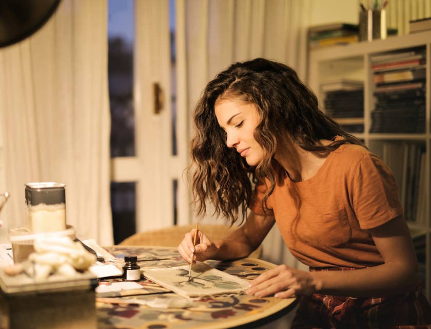 An illustrator painting a design on a piece of paper.