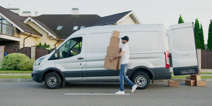A delivery driver carrying parcels to a designated delivery point from his truck.