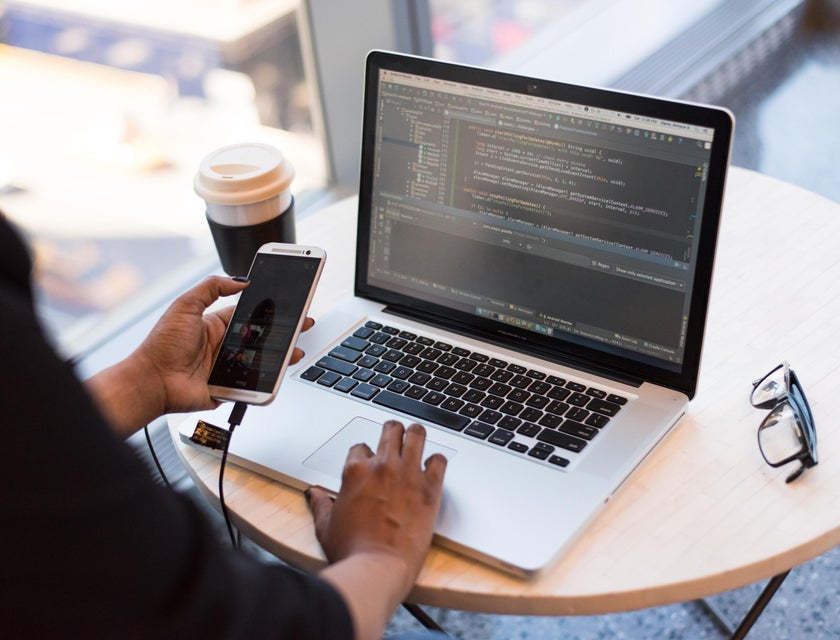 A Magento developer working with a cellphone in hand.