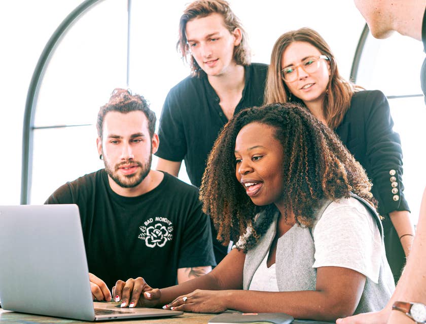A group of colleagues watching a marketing assistant's presentation on a laptop.