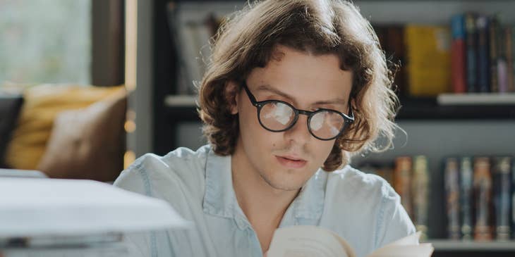 Historian reading several books in a library.