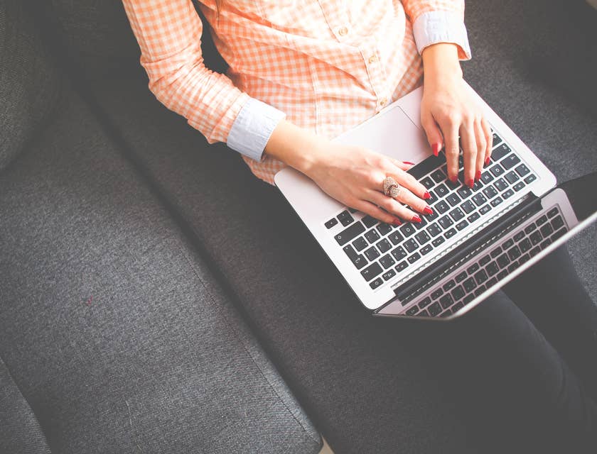 Data entry typist working on a laptop and sitting on a couch at home