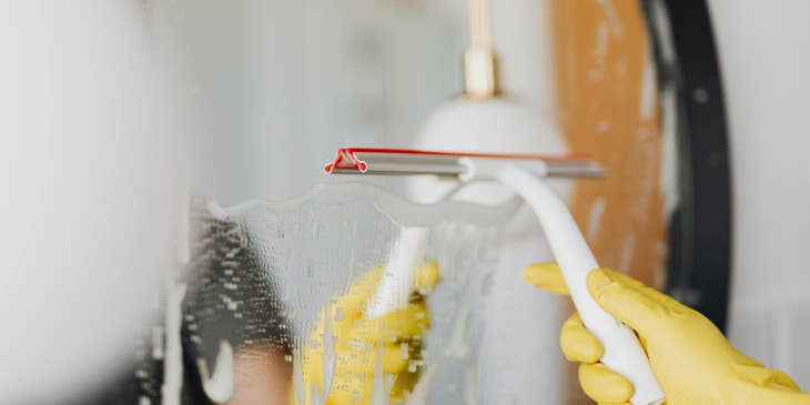 Homemaker cleaning a bathroom mirror