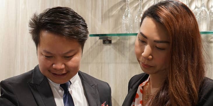 A hospitality manager and co-worker looking at a schedule and writing a note.