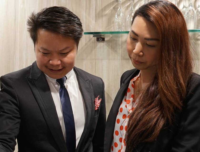 A hospitality manager and assistant looking at a schedule and writing a note.