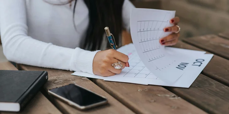 A hospitality manager looking at a schedule and writing a note.