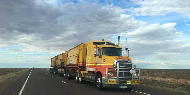 A CDL driver driving a truck on an empty road.
