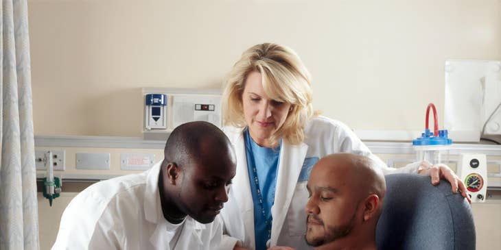 assistant nurse looking on as nurse administers medication to patient