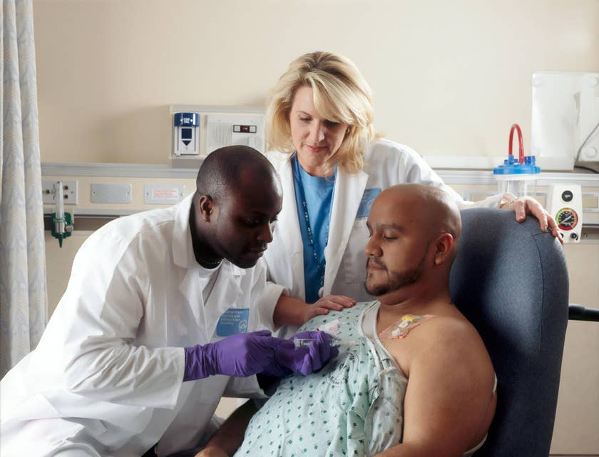 assistant nurse looking on as nurse administers medication to patient
