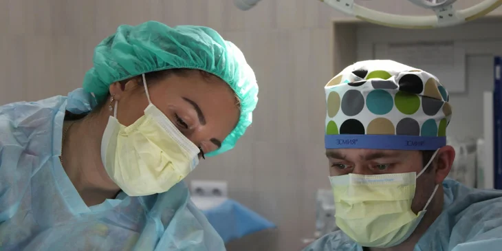 A surgeon with a nursing assistant in an operating room.