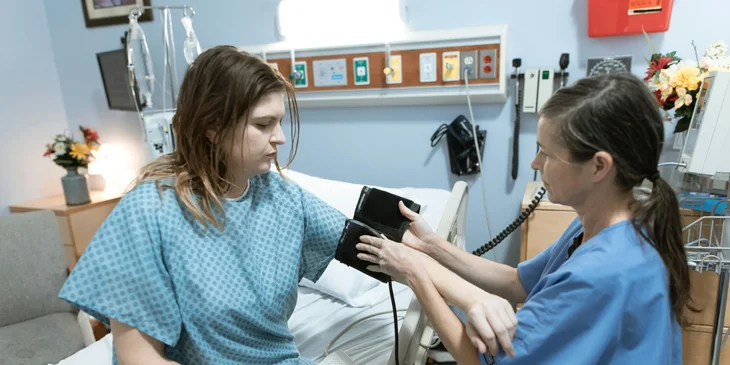 A registered nurse about to check a patient's blood pressure.