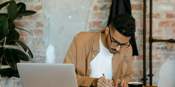 An HR intern in an office setting taking notes.