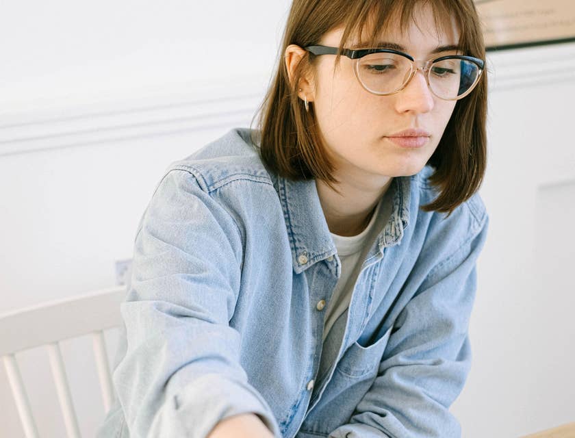 An HR Intern in an office setting looking at a laptop and taking notes.