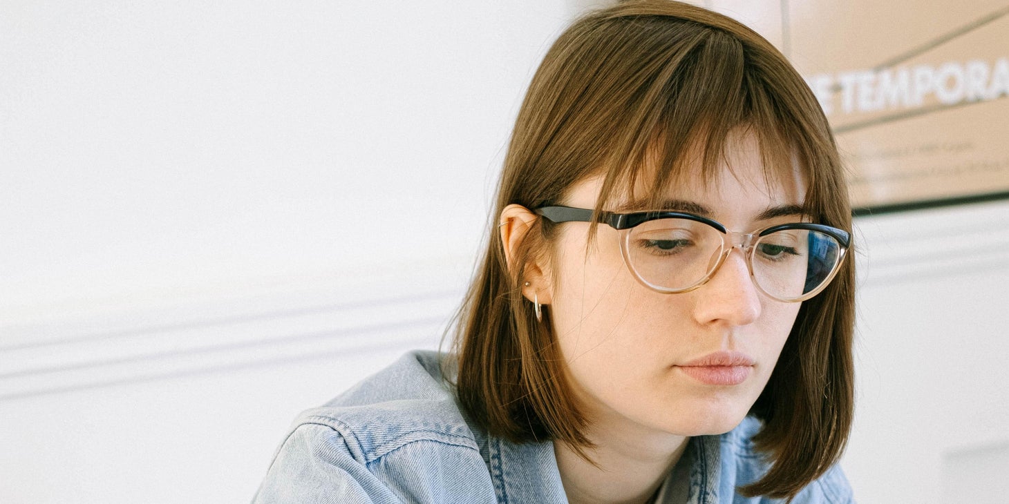 An HR Intern in an office setting looking at a laptop and taking notes.