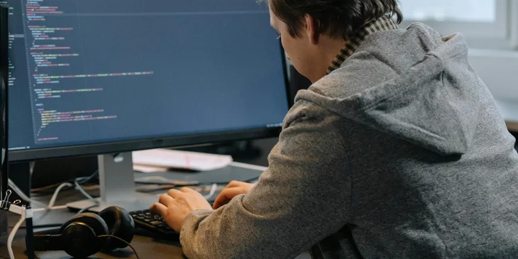 An HRIS analyst on his computer working on a software.
