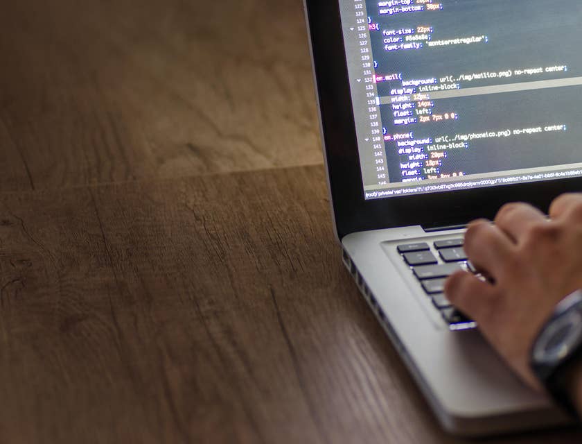 An HRIS Analyst on his laptop working on a software.