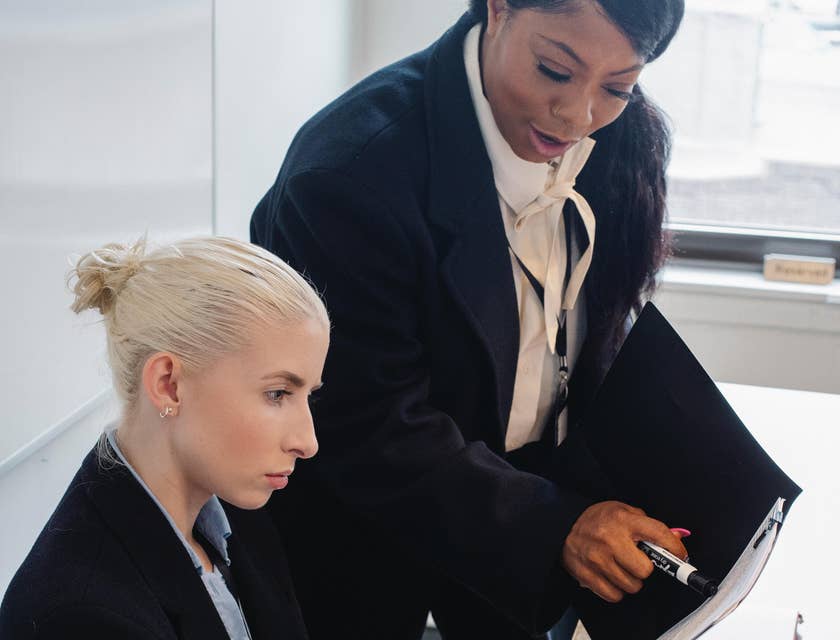A Female Immigration Paralegal reporting and presenting visa petition document to an Immigration Program Manager.