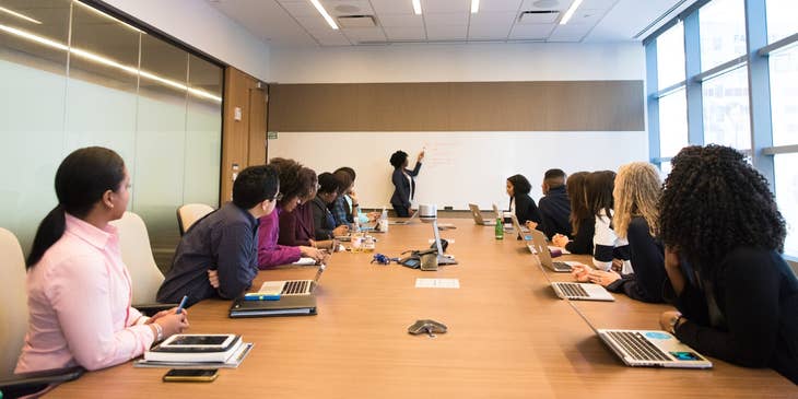 Information Security Officer cascading new security measures for data protection inside the conference room with the rest of the team looking on