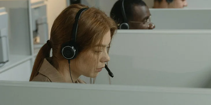 A group of insurance customer service representatives in a call center setting with headsets on answering calls.