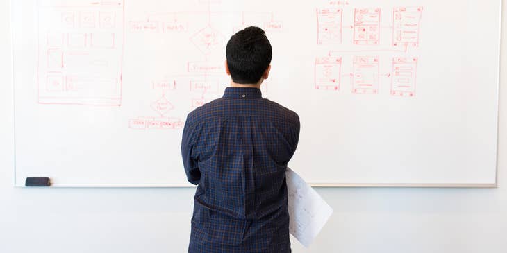 IT Architect looking at the network system design written at the whiteboard before implementing the upgrades