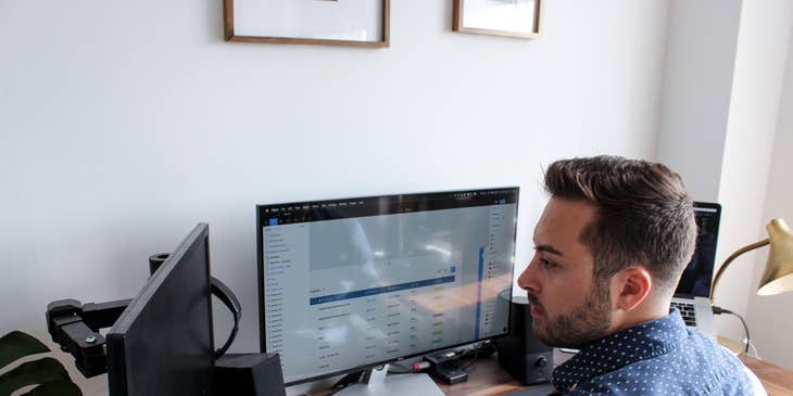 IT Auditor sitting at his workstation and reviewing the overall information system reports