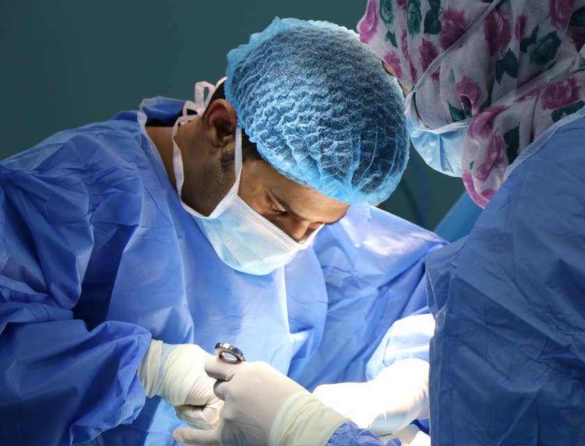 Médicos especialistas usando uniformes azules en una sala de operaciones.