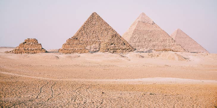 Desert with pyramids in background.