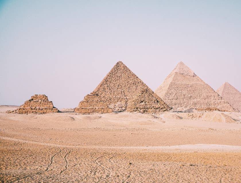 Desert with pyramids in background.