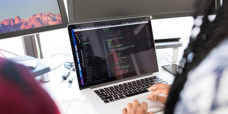 jQuery developer working on her laptop and sitting beside a colleague