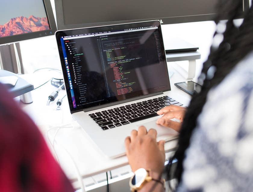 jQuery developer working on her laptop and sitting beside a colleague