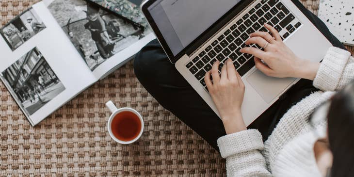 Junior copywriter typing an article while drinking tea