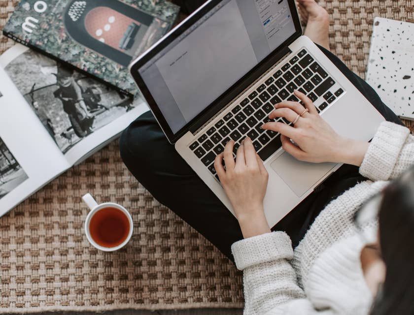 Junior Copywriter typing an article while drinking tea